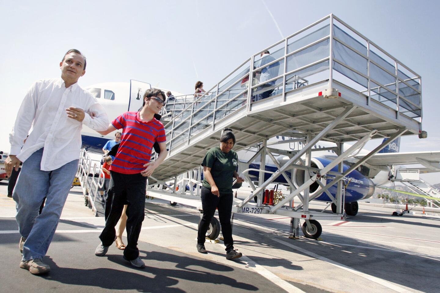 German Barrero, from far left, takes hold of his son, Alessandro, 15, who is autistic, while departing the plane during Jet Blue, Pacific Child and Family and TSA's "Wings for Autism" program, which took place at Bob Hope Airport in Burbank on Saturday, May 4, 2013. JetBlue Airways began "Wings for Autism" in Boston for the last three years and brought the program to California for the first time. Families with autistic children are often fearful of traveling due to the stress that parents may go through. Anxiety, long lines, loud noises and unfamiliarity may affect autistic children. About one in 88 children are autistic.