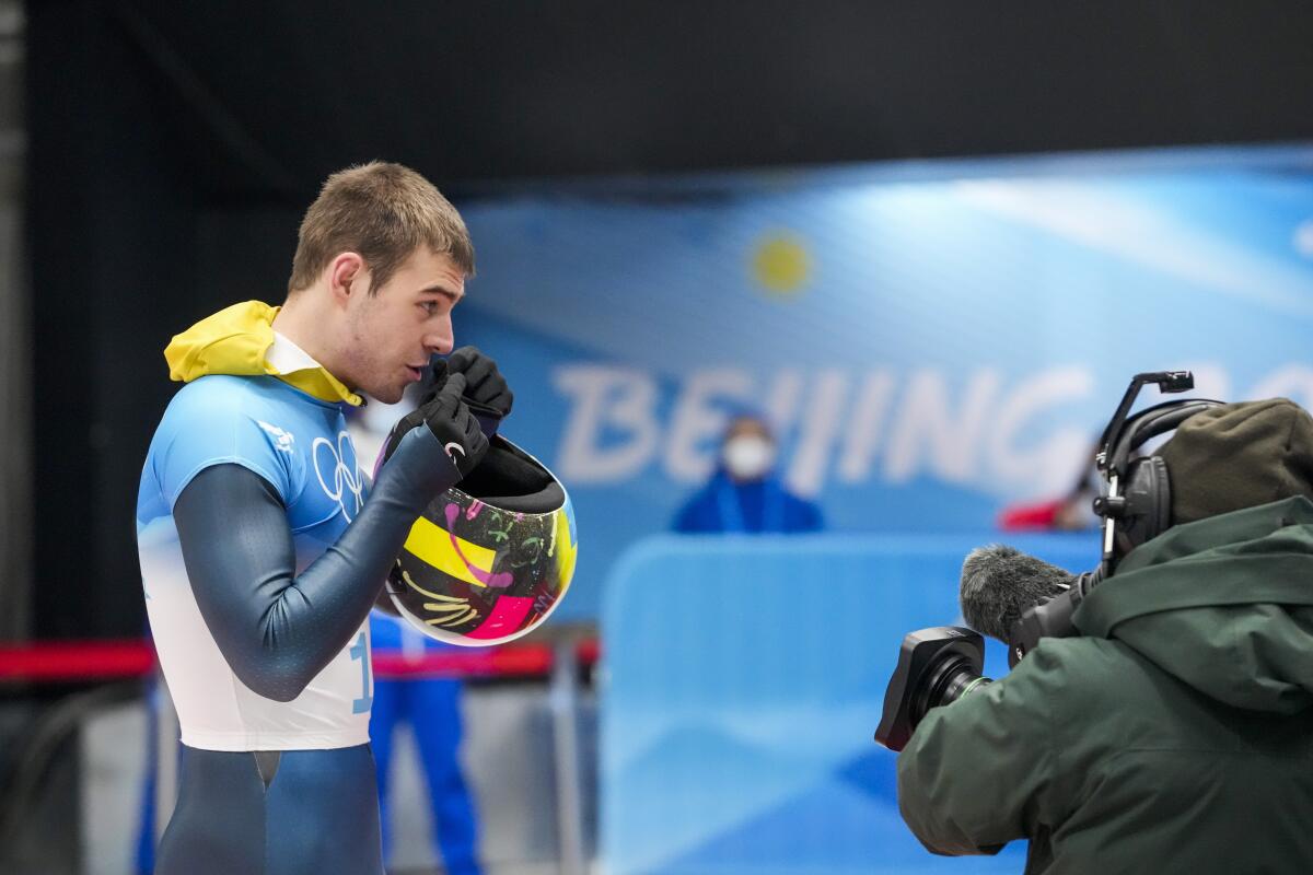 Vladyslav Heraskevych, of Ukraine, stands in the mixed zone after finishing the men's skeleton run 4 at the 2022 Winter Olympics, Friday, Feb. 11, 2022, in the Yanqing district of Beijing. (AP Photo/Mark Schiefelbein)