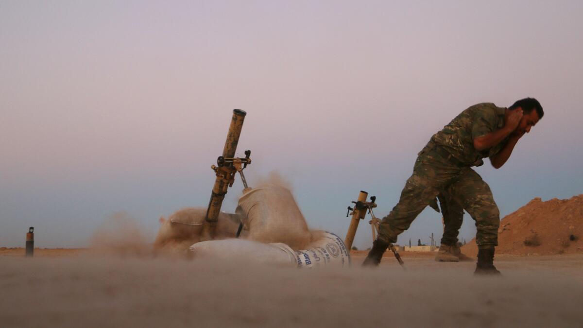 A rebel from the Free Syrian Army protects his ears during mortar fire in fighting against Islamic State on the outskirts of Dabiq, Syria.