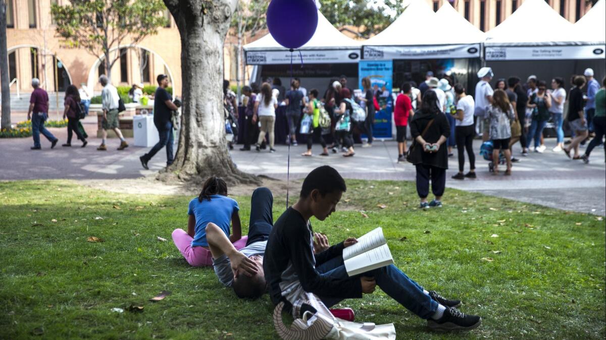 Adix Hu, 12, and his sister, Amy Hu, 9, read books while their father, Xiao Hu naps, during the 2018 Los Angeles Times Festival of Books on the USC campus.