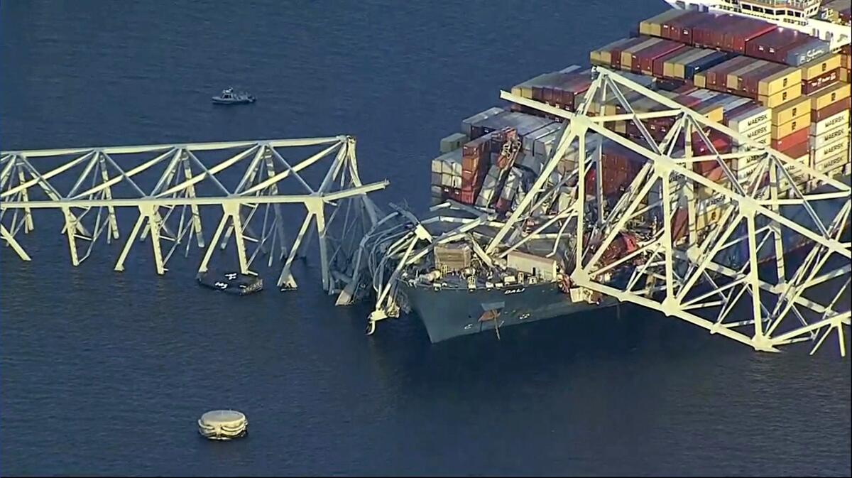 A collapsed bridge lies atop a cargo ship. 