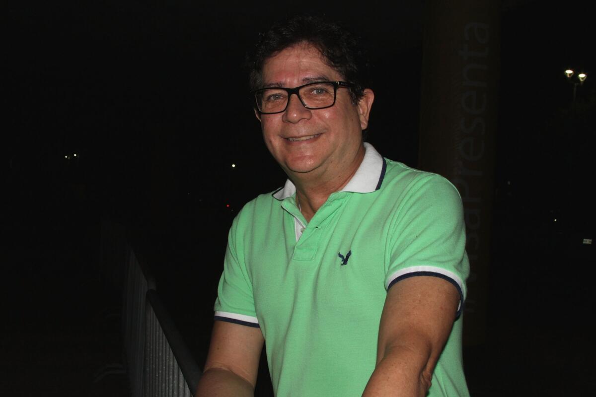 Edgardo Díaz is framed waist up, wearing a polo T-shirt, glasses, looking at the camera and smiling.