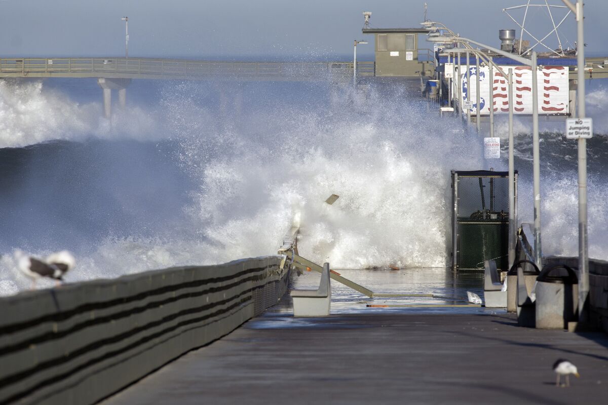Waves crash over the Ocean Beach Pier on Jan. 11, damaging railings.