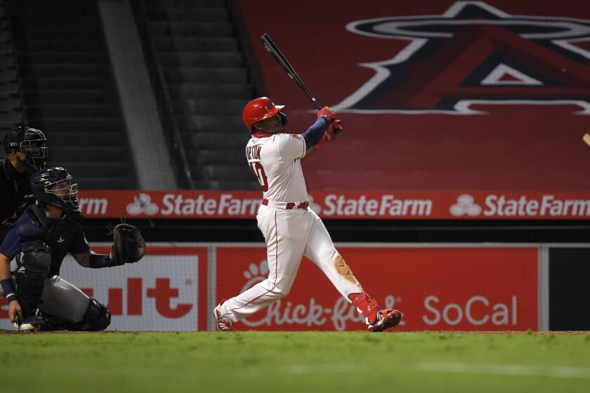Los Angeles Angels' Justin Upton, right, hits a solo home run as Seattle Mariners catcher Joseph Odom, center, and home plate umpire Edwin Moscoso watch during the sixth inning of a baseball game Wednesday, July 29, 2020, in Anaheim, Calif. (AP Photo/Mark J. Terrill)