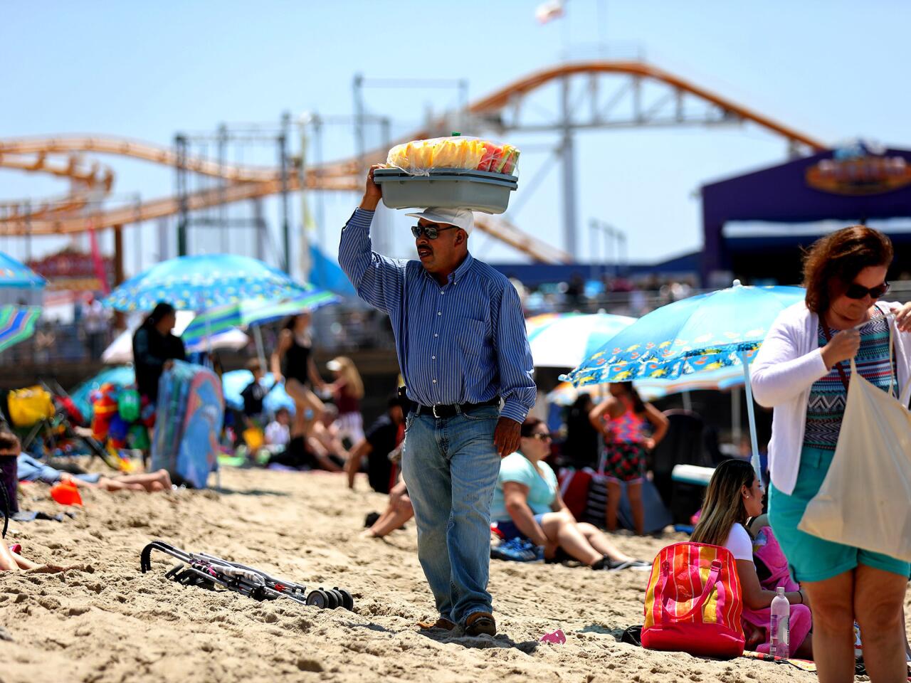 A vendor sells fruit to beachgoers in Santa Monica. Some licensed vendors working around the pier say a new ordinance that can penalize them for blocking access ways has made them nervous about being arrested.