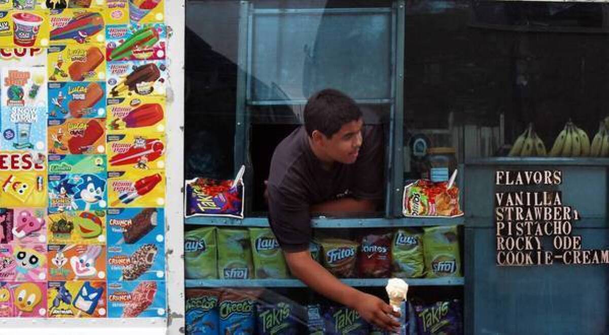 Felipe Hernandez, 15, helps his father serve ice cream from their truck in Long Beach. Some vendors have expressed concern about Long Beach's move to restrict ice cream truck music, saying the jingles are the only way to alert customers that their trucks are nearby.