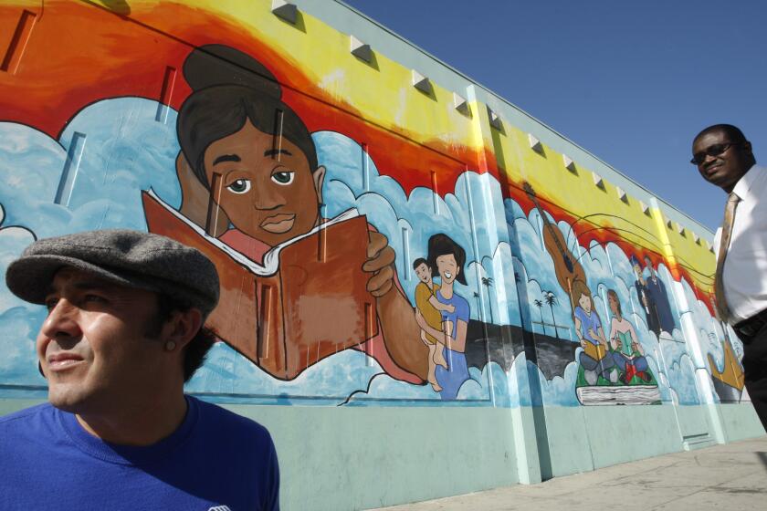 Artist Eduardo Lalo Marquez, left, and Mortimer Jones, executive director of the Salvation Army Siemon Youth & Community Center, stand infront of Marquez' mural.
