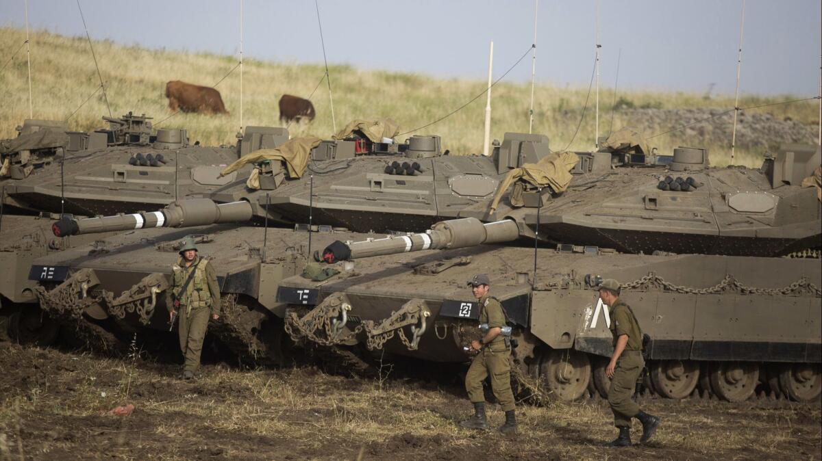 Israeli soldiers next to Merkava tanks deployed near the Israeli-Syrian border in the Golan Heights.