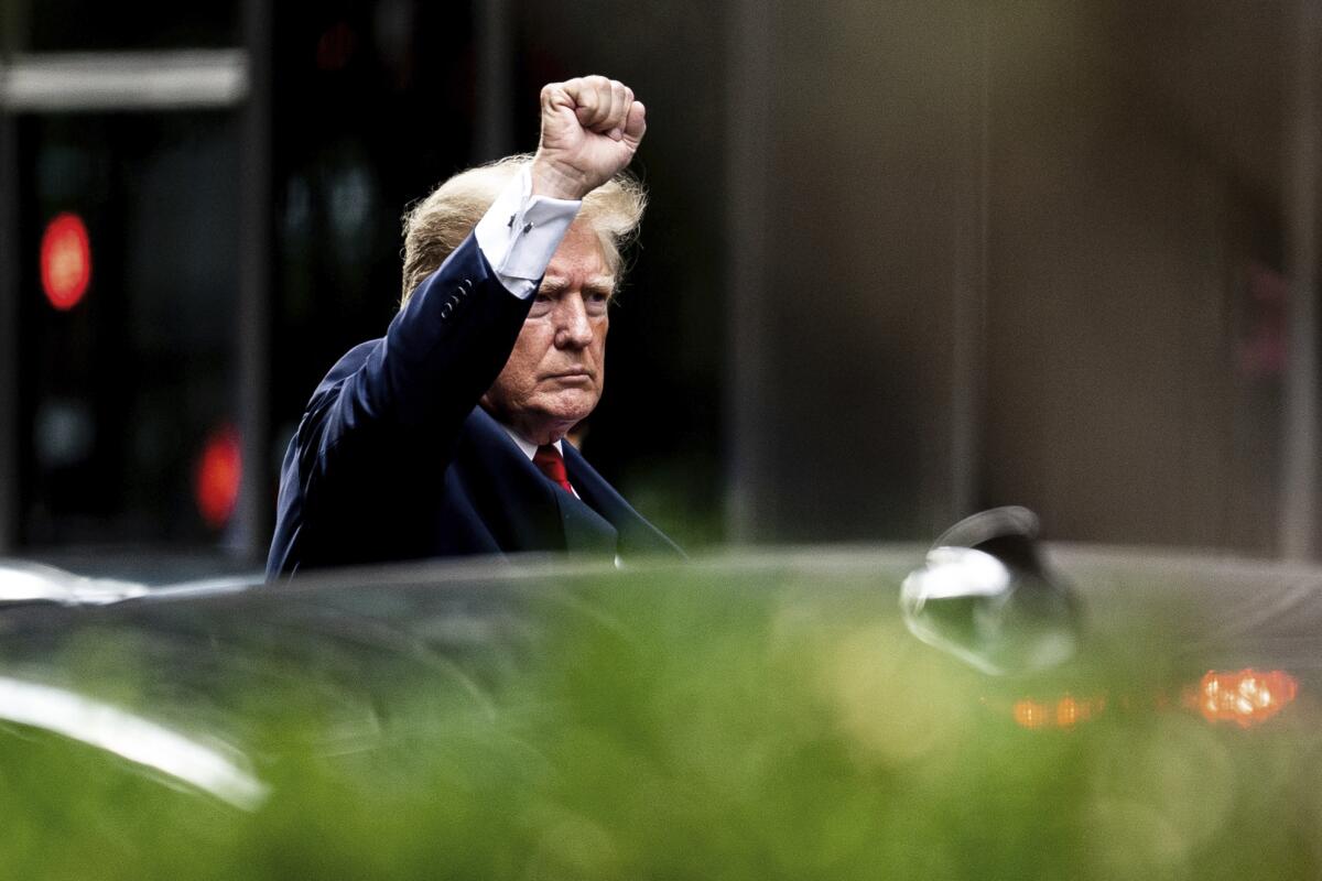 El expresidente Donald Trump alza el puño al salir de la Trump