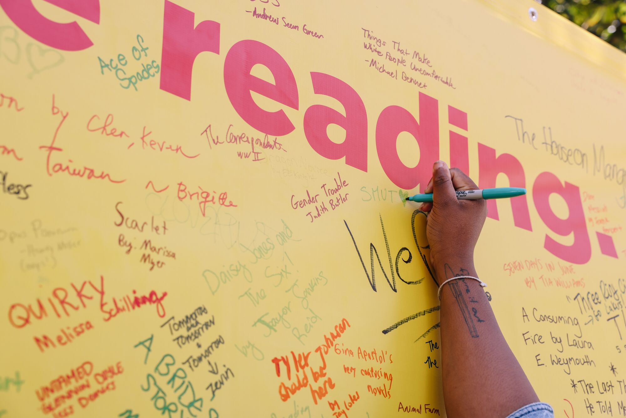 People fill a board with titles of book they love or are currently reading.