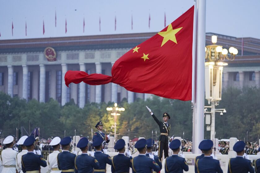 In this photo released by Xinhua News Agency, a member of the Chinese honor guard unfurls the Chinese national flag during a flag raising ceremony to mark the 73rd anniversary of the founding of the People's Republic of China held at the Tiananmen Square in Beijing on Saturday, Oct. 1, 2022. (Chen Zhonghao/Xinhua via AP)