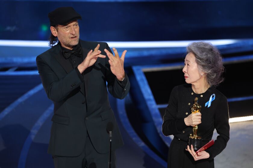 HOLLYWOOD, CA - March 27, 2022. Troy Kotsur accepts the Actor in a Supporting Role award for ‘CODA’ from Youn Yuh-jung during the show at the 94th Academy Awards at the Dolby Theatre at Ovation Hollywood on Sunday, March 27, 2022. (Myung Chun / Los Angeles Times)