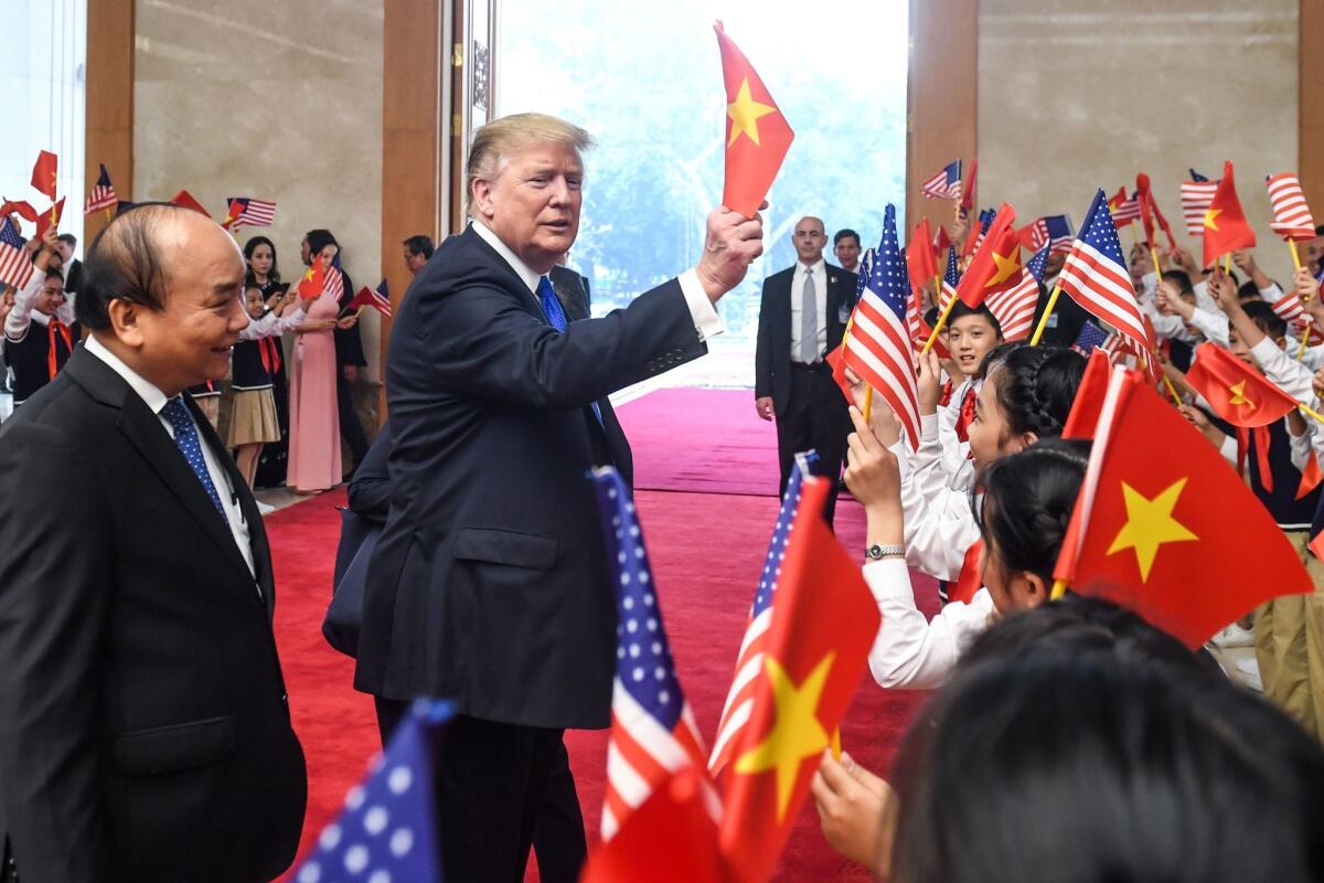 President Trump waves a Vietnamese flag as the nation's prime minister, Nguyen Xuan Phuc, looks on in Hanoi on Wednesday.