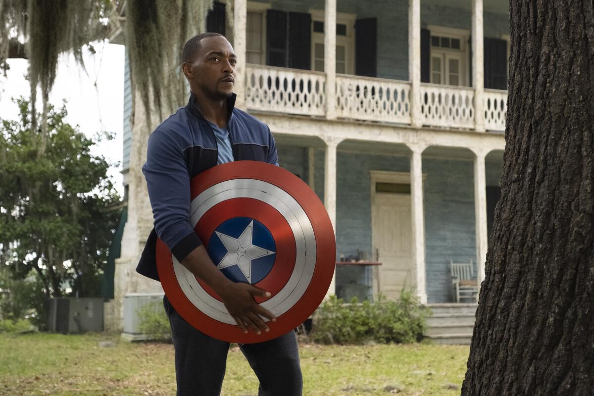 A man holding a shield in front of a house