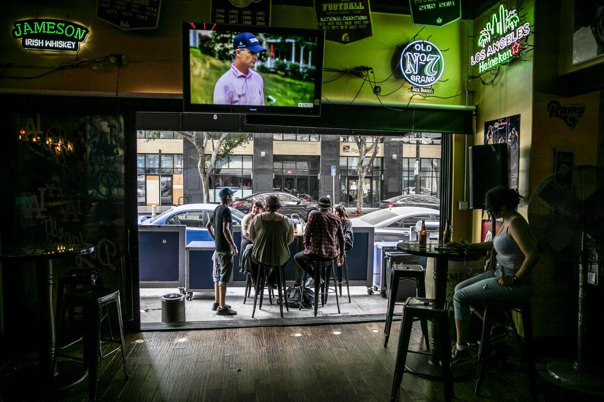 Patrons drink at an outside patio Sunday at the Down & Out sports bar in downtown L.A. 
