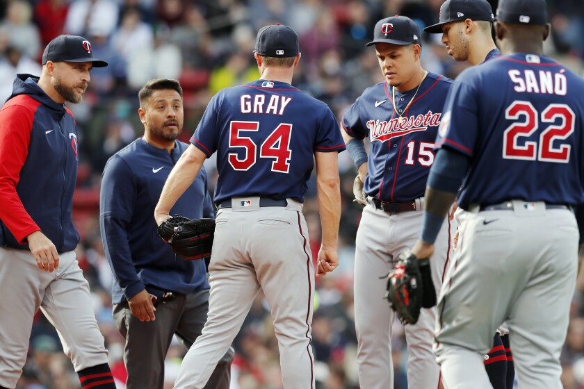 Minnesota Twins manager Rocco Baldelli, left, comes to the mound with a trainer to talk with Sonny Gray (54) during the second inning of a baseball game against the Boston Red Sox, Saturday, April 16, 2022, in Boston. Gray left the game. (AP Photo/Michael Dwyer)