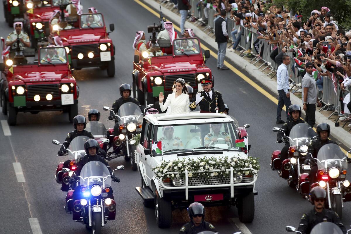 Newlyweds Rajwa al Saif and Jordan's Crown Prince Hussein wave to well-wishers as they ride in a motorcade.