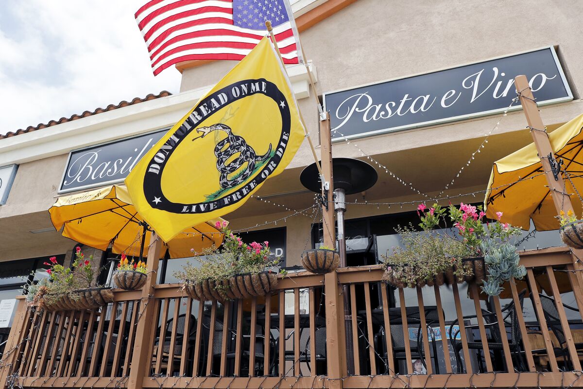 A Gadsden flag is hung with the flag of the United States of America at Basilico's Pasta e Vino in Huntington Beach. 