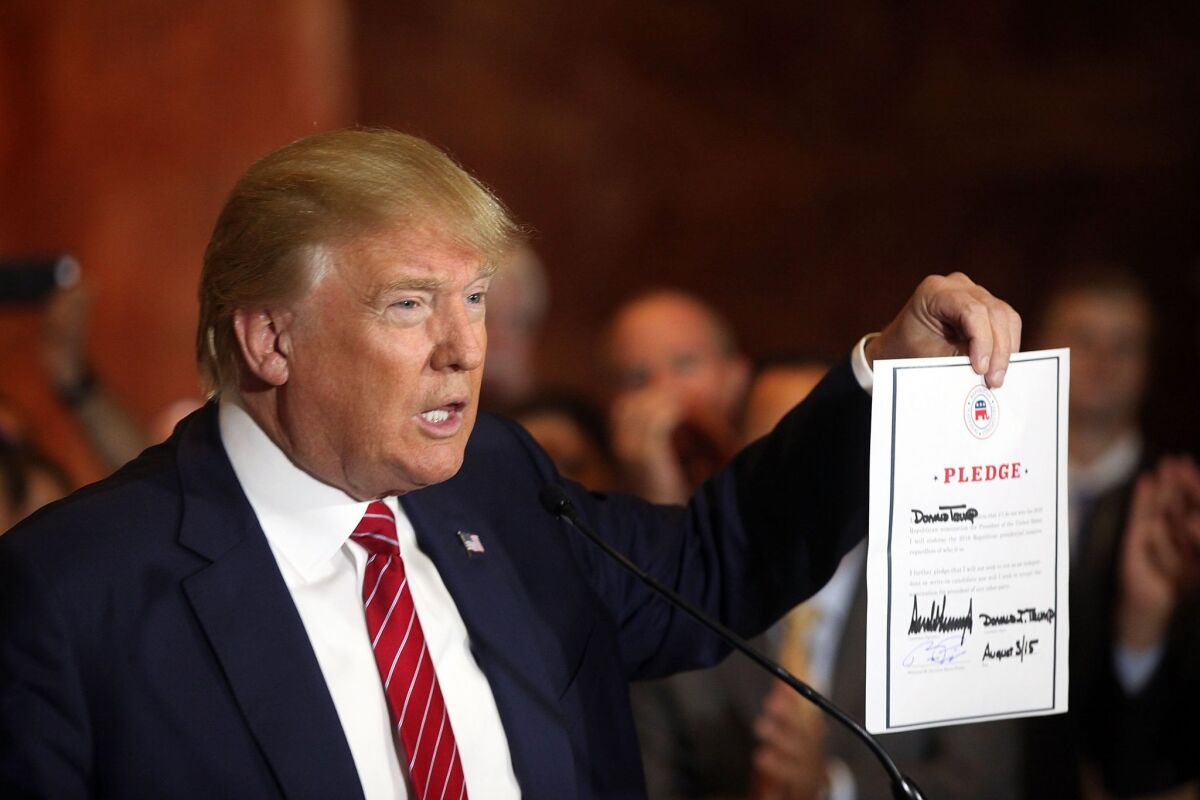 GOP presidential front-runner Donald Trump holds up a pledge to support the Republican nominee in the 2016 general election, ruling out a third-party or independent run, in New York City on Sept. 3, 2015.
