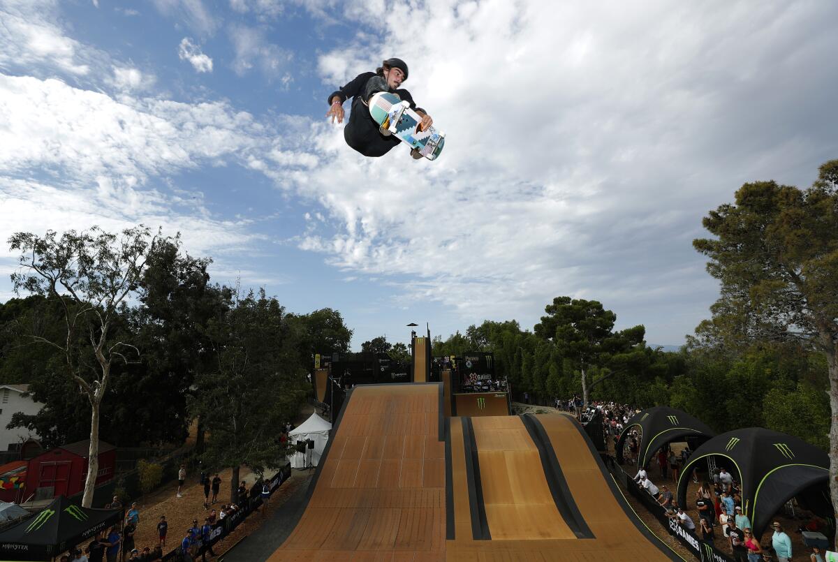 A man on a skateboard hovers above a large ramp surrounded by spectators