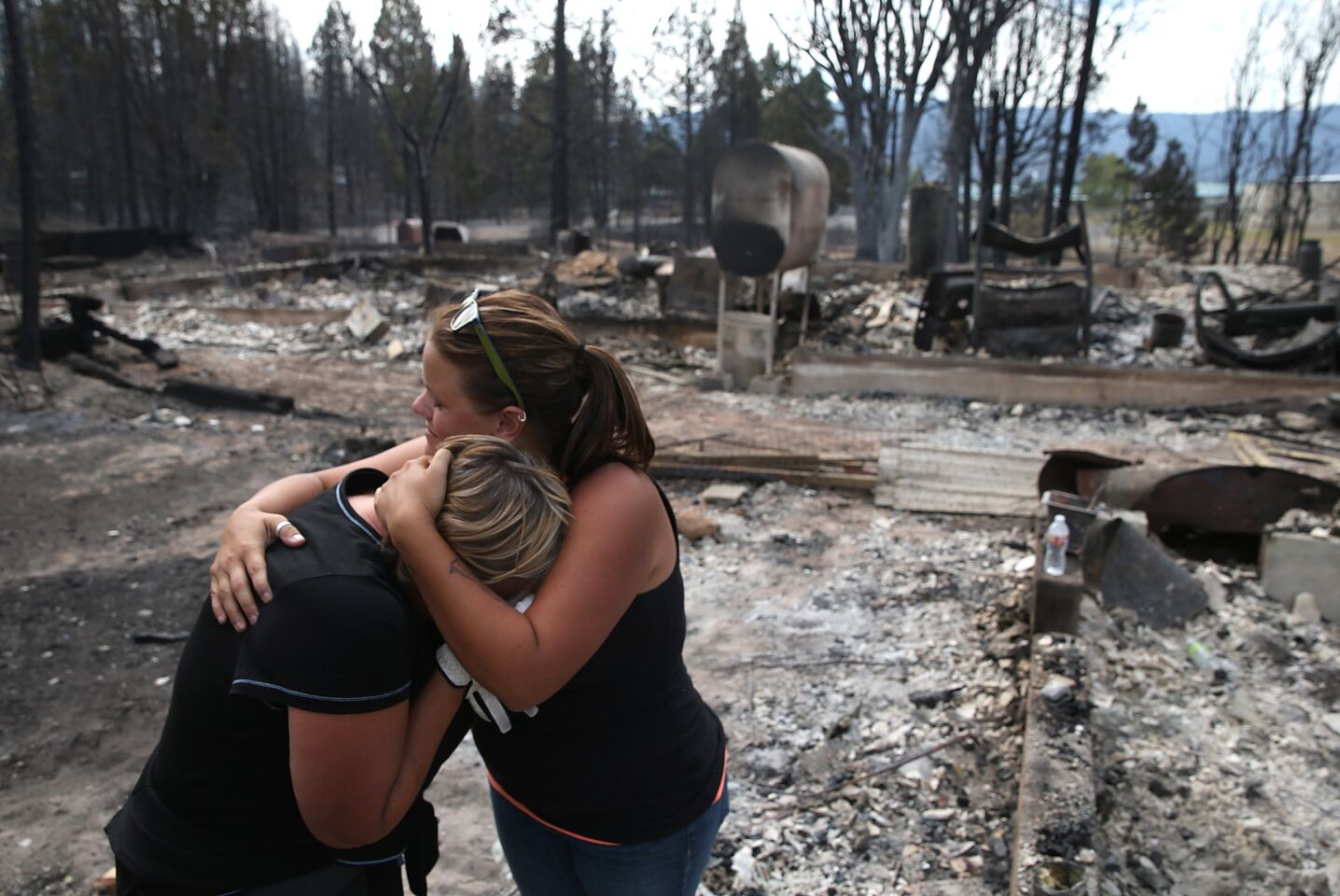 Kathy Besk, left, cries with her daughter Shelley Besk as they stand in the burned-out ruins of their home in Weed, Calif.