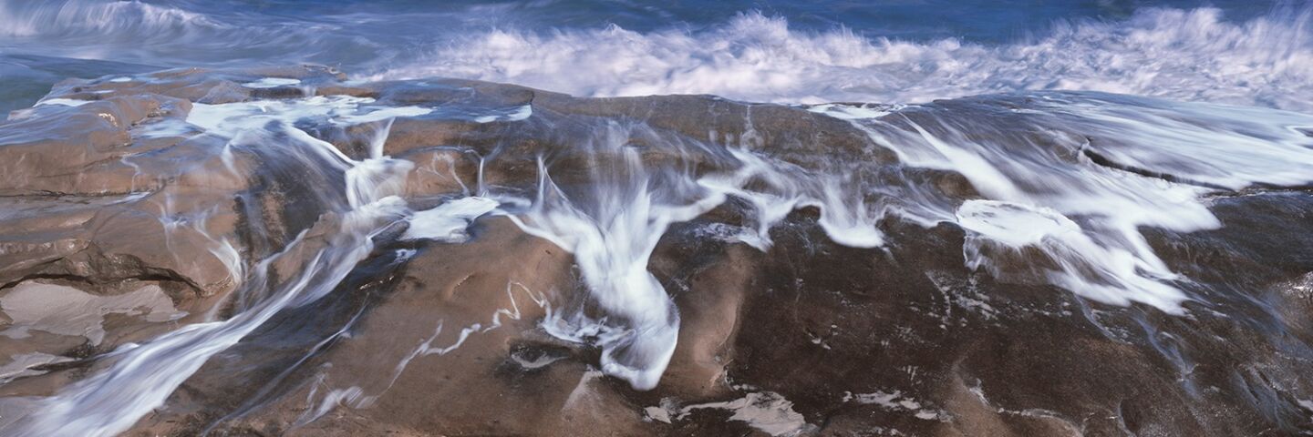 A tidal surge pours over the rocks at Windansea.