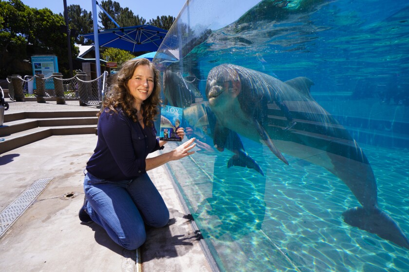 Author Joy Clausen Soto poses with dolphins at SeaWorld San Diego's Dolphin Point.