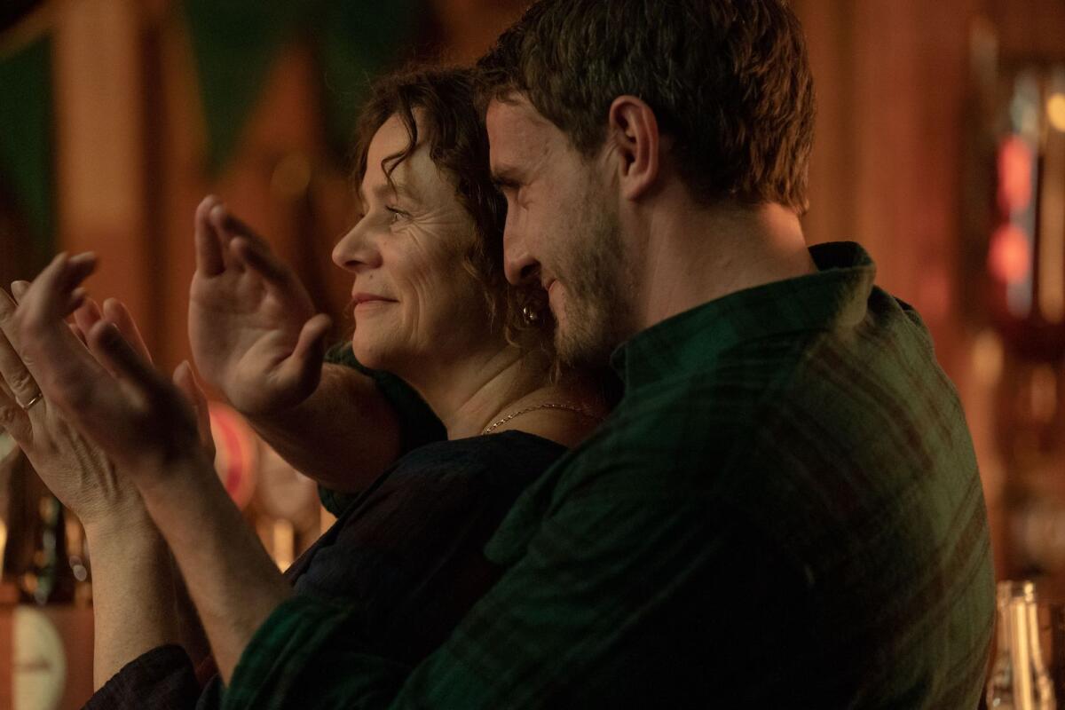 A woman and a man clapping with his arm around her shoulder in the movie "God's Creatures."