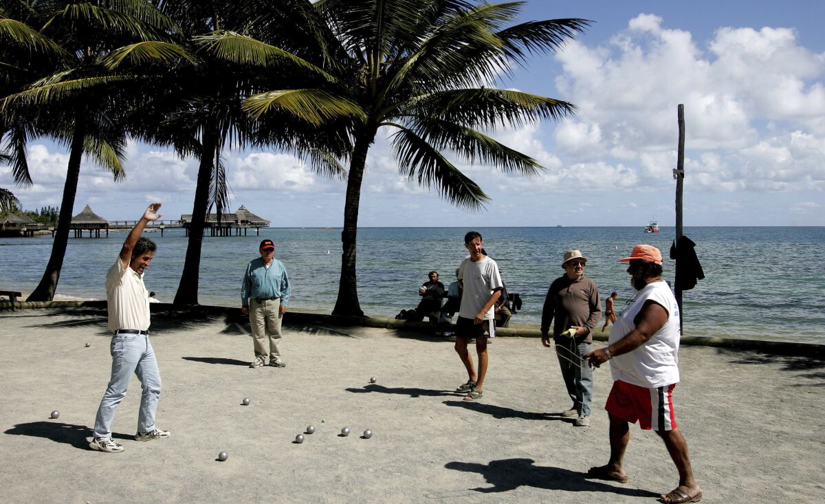 FILE - In this Thursday, Sept. 22, 2005 file photo, locals on the beach in Noumea, New Caledonia, play the traditional ball game "petanque". Voters in New Caledonia, a French archipelago in the South Pacific, are to choose whether they want independence from France in a referendum that marks a milestone in a three-decades-long decolonization effort. The vote on Sunday, Oct. 4, 2020 is key to determine the future of the archipelago east of Australia and its 270,000 inhabitants, including the native Kanaks, who once suffered from strict segregation policies, and the descendants of European colonizers. (AP Photo/Rob Griffith, file)