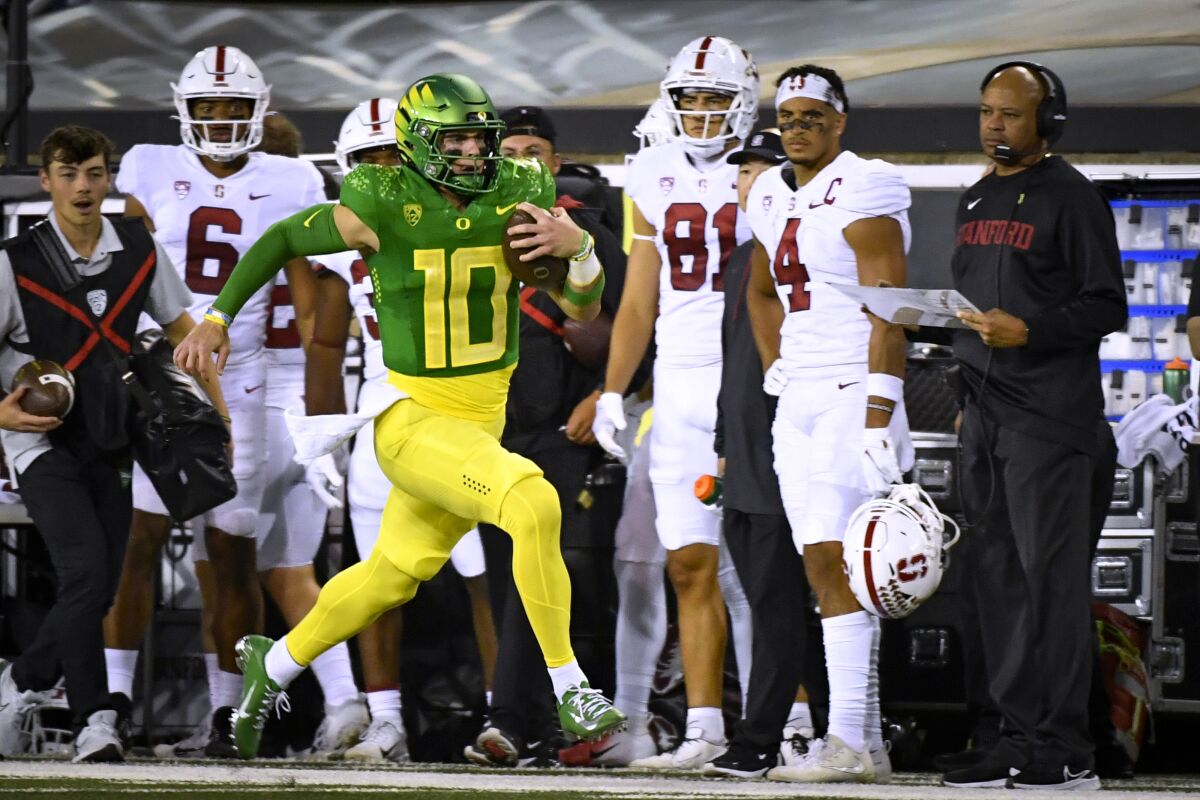Oregon quarterback Bo Nix (10) runs past Stanford coach David Shaw, right, on a long gain during the first half of an NCAA college football game Saturday, Oct. 1, 2022, in Eugene, Ore. (AP Photo/Andy Nelson)