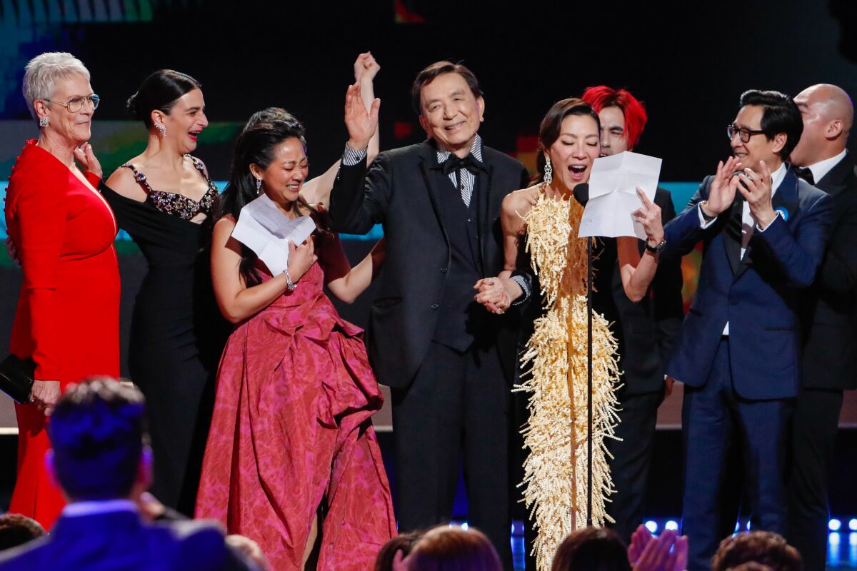 A group of people in formalwear rejoicing onstage.