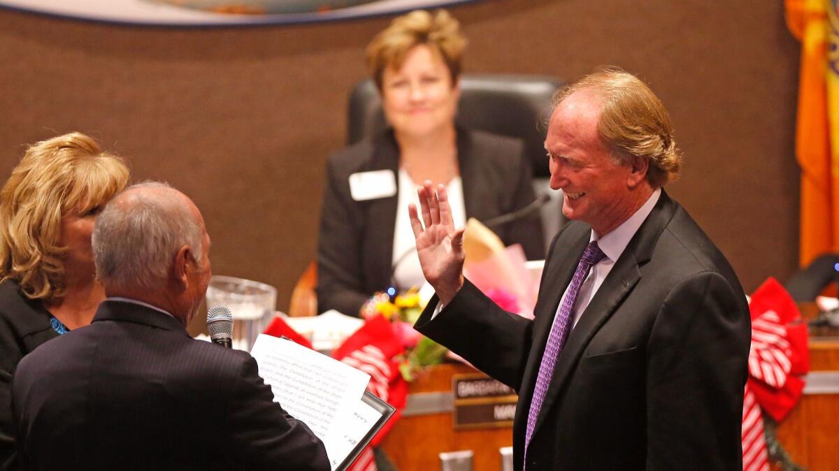 Mike Posey, who had been mayor pro tem, is sworn in as Huntington Beach mayor on Monday night as outgoing mayor Barbara Delgleize looks on.