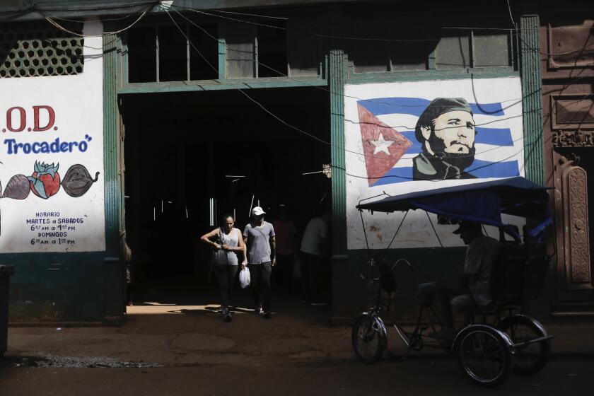 Shoppers exit a state-run agro-market, where a mural of Fidel Castro adorns the facade, in Havana, Cuba, Thursday, March 7, 2024. Many Cubans feel ill-equipped to handle their new, more unequal country, a feeling that has worsened as small private markets have opened, charging prices similar to international ones in a country that hasn’t allowed non-state commerce in recent decades and where incomes remain between $16 and $23 monthly. (AP Photo/Ariel Ley)
