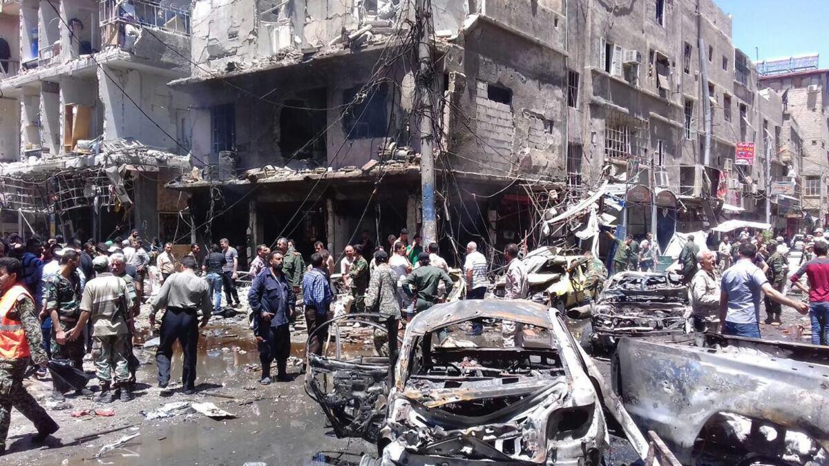 Residents and soldiers inspect the site of a bombing in the Sayyida Zeinab area south of Damascus, Syria.