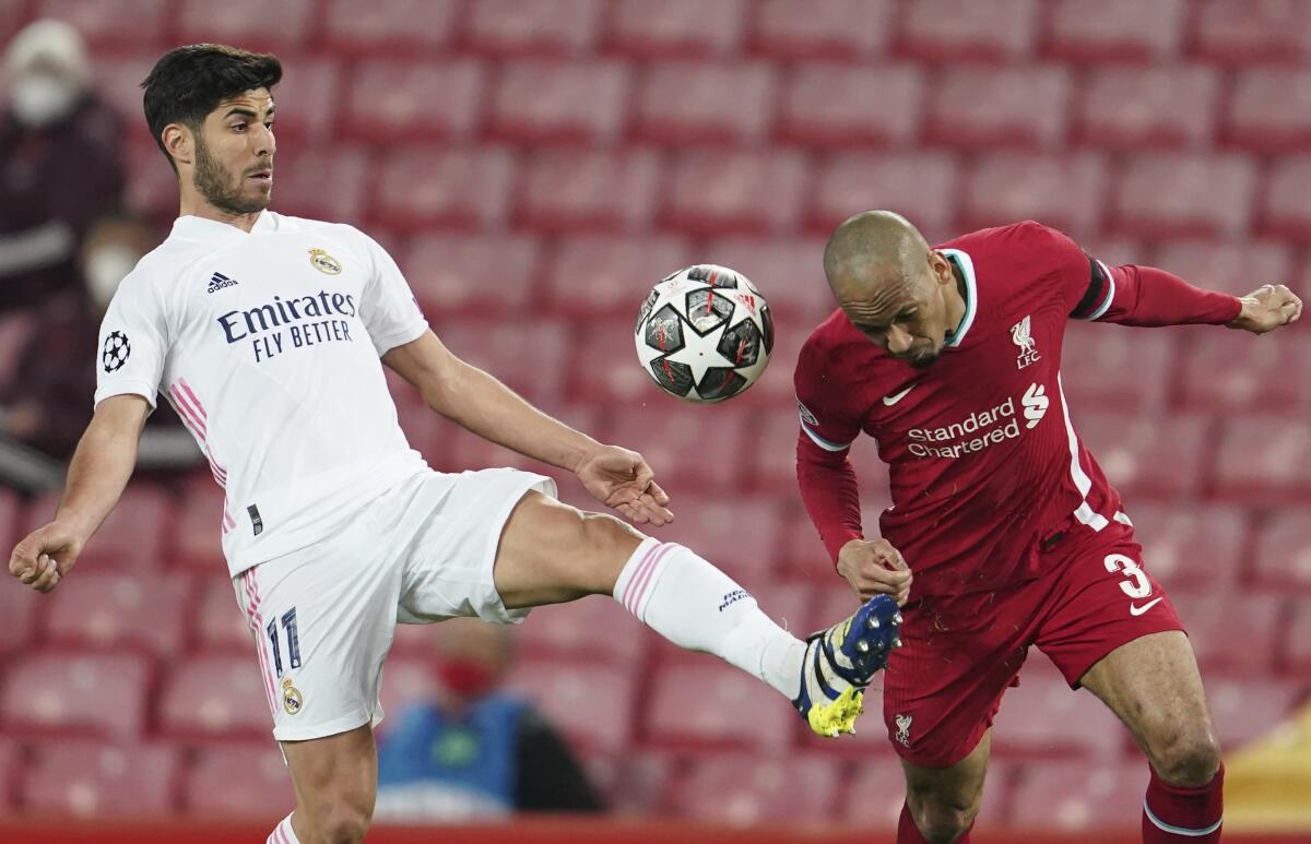 En esta foto del 14 de abril de 2021, Marco Asensio, del Real Madrid, disputa un balón con Fabinho, del Liverpool