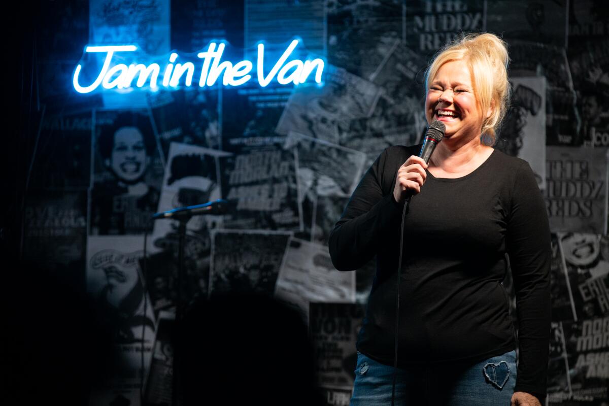 A woman holds a microphone onstage