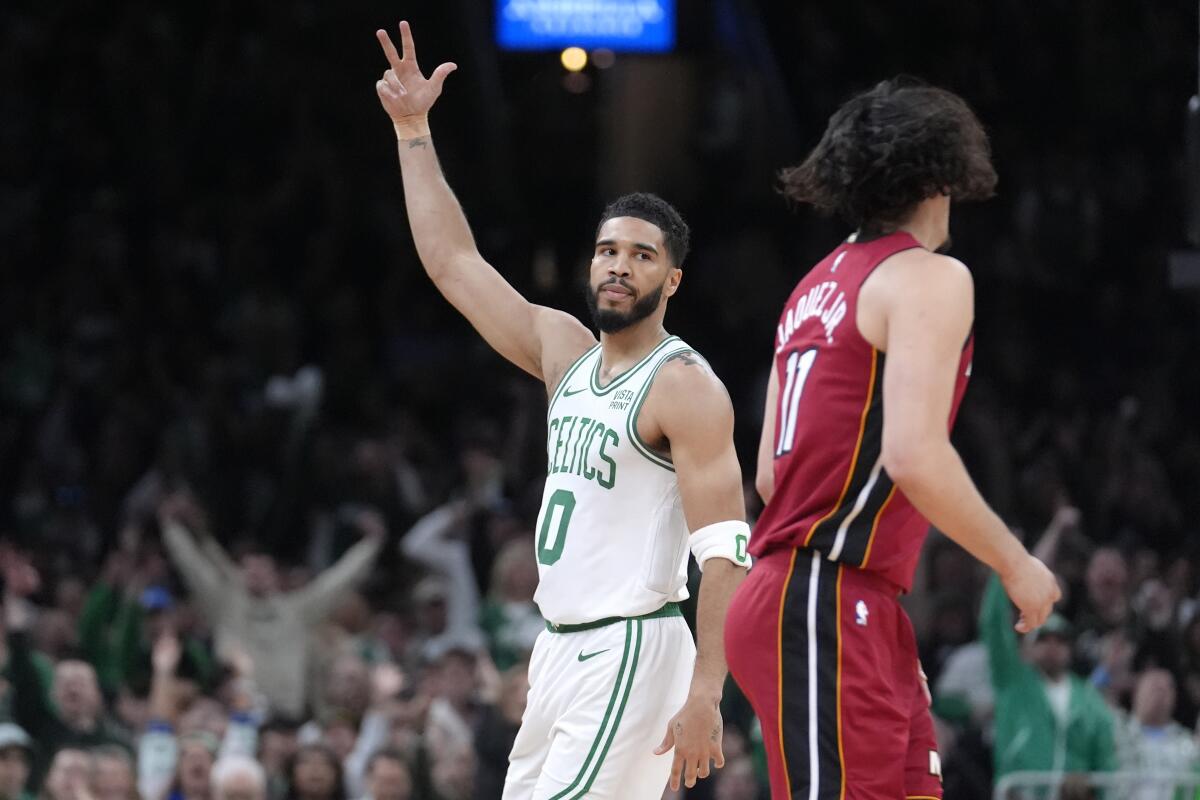 El alero de los Celtics de Boston Jayson Tatum (0) celebra frente al armador mexicano del Heat 
