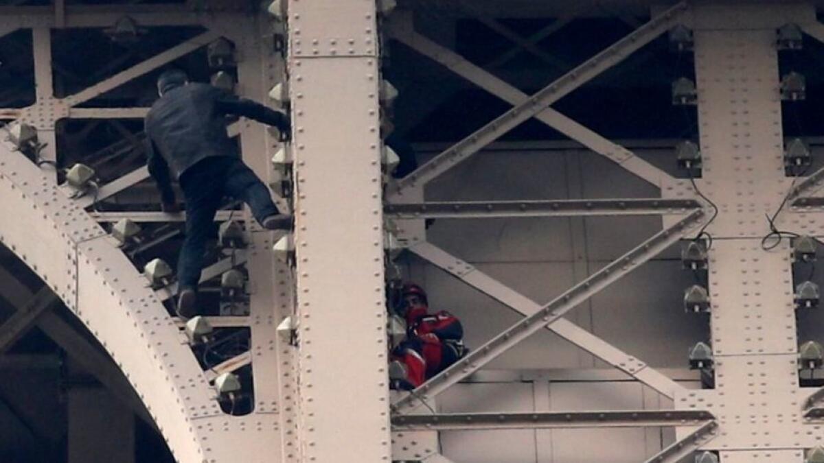 A man climbs the Eiffel Tower in Paris while a rescuer in red tries to communicate with him on May 20, 2019.
