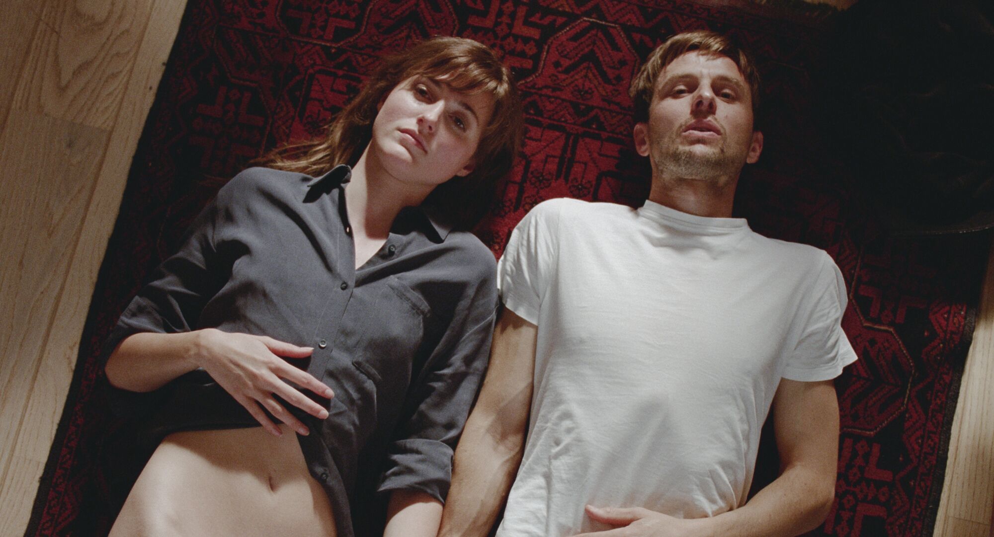 A man and a woman lying on the ground next to each other.