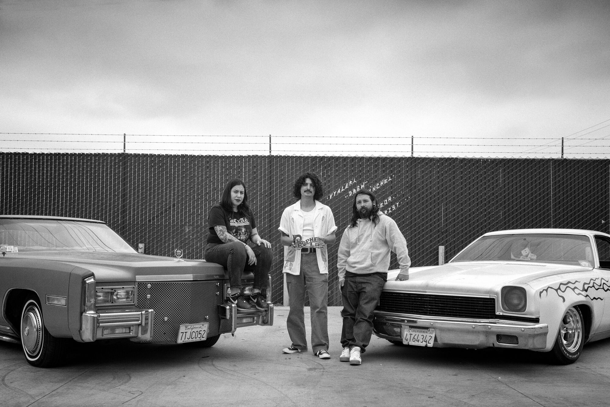Jacqueline Valenzuela, Jesse Jaramillo, and Mark Hocutt posing by their two classic cars