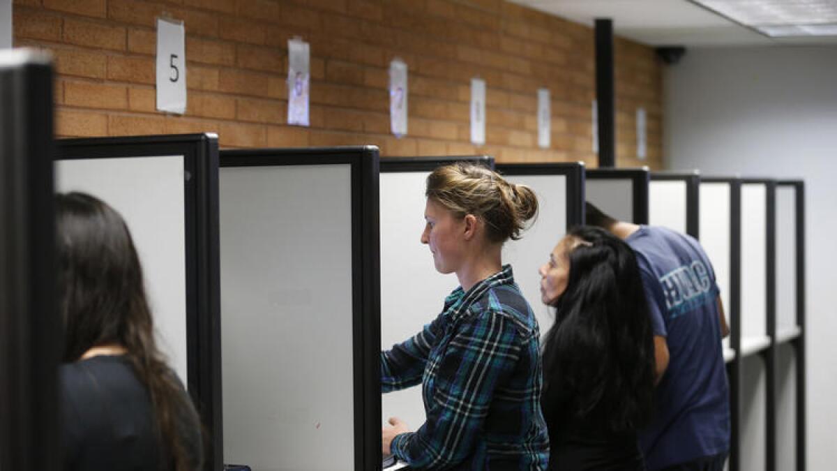 Glenn Woerndle (centro), de Orange, se registra para votar y hace su examen de conducir utilizando una máquina de pantalla táctil en Santa Ana.