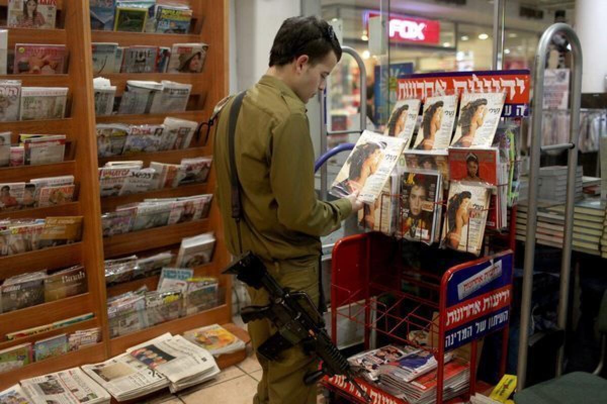 An Israeli soldier looks at a Playboy magazine in a kiosk in Jerusalem.