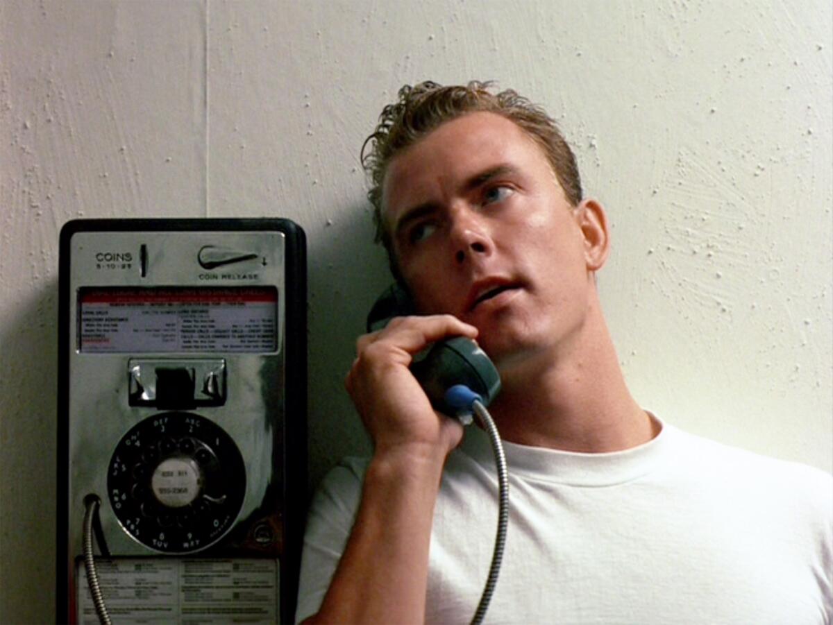 Barry Tubb talks on a payphone in a white T-shirt in a scene from the original 'Top Gun'