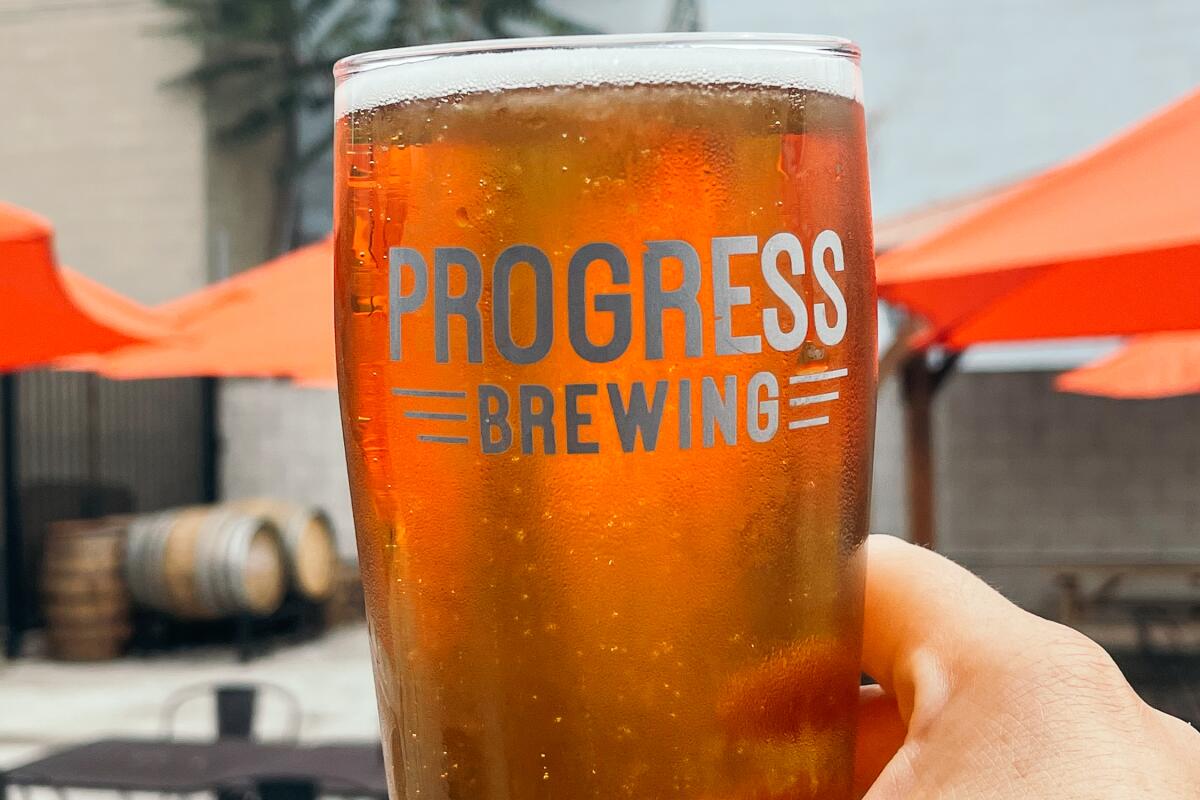Progress Brewing, South El Monte: Author holding pint of Alamo Munich Helles, patio at brewery