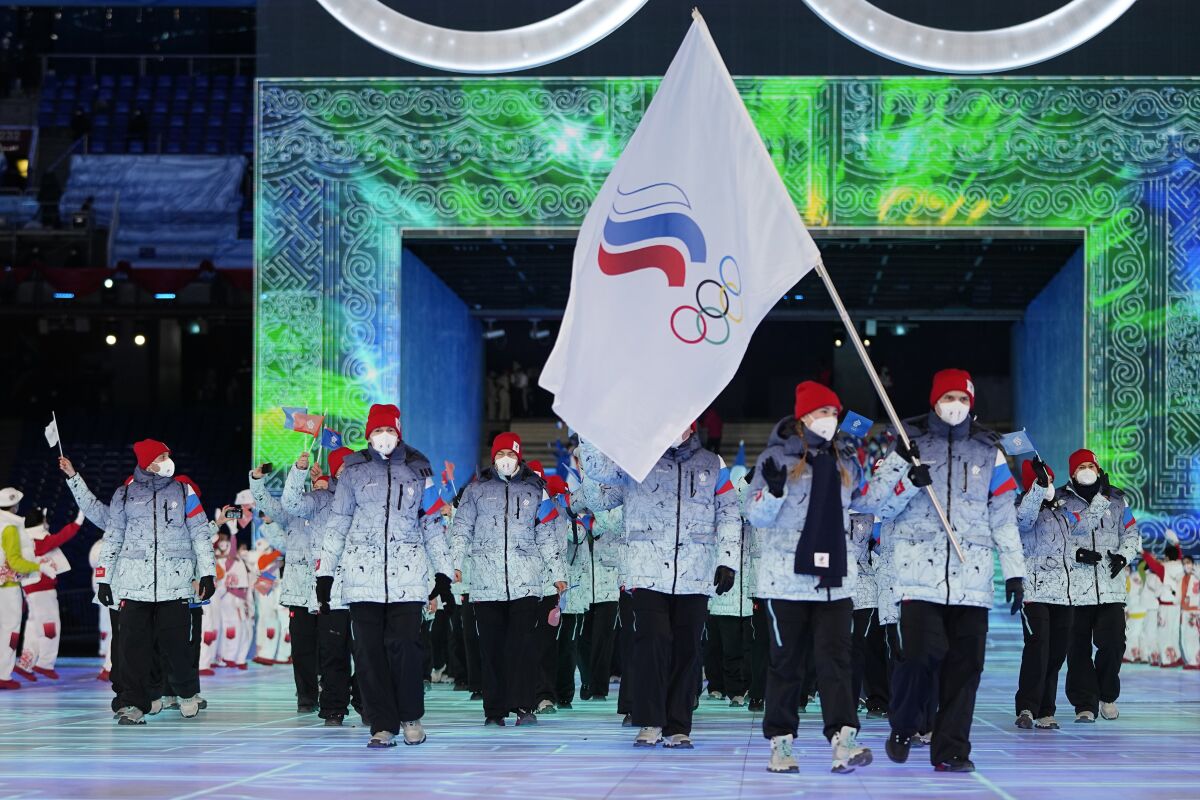 FILE- Olga Fatkulina and Vadim Shipachyov, of the Russian Olympic Committee, carry a flag into the stadium during the opening ceremony of the 2022 Winter Olympics, Friday, Feb. 4, 2022, in Beijing. Russian athletes are competing under the acronym ROC, for Russian Olympic Committee, for the third time. The national colors and flag are banned by the International Olympic Committee because of a massive state-sponsored doping operation during the 2014 Sochi Games, which Russia hosted. (AP Photo/Jae C. Hong, File)