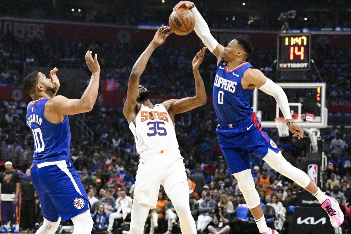 Clippers guard Russell Westbrook reaches for a loose ball above Suns forward Kevin Durant.