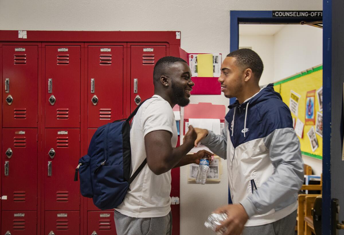 Damion Lester Jr., left, greets a former classmate as he leaves school for the day at Washington Prep High School.