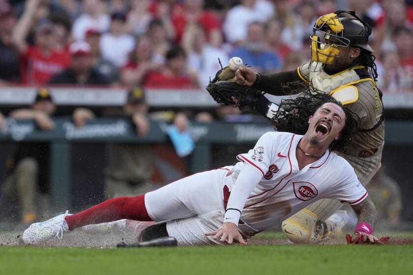 Cincinnati Reds' Jonathan India reacts as he collides with San Diego Padres catcher Luis Campusano during the second inning of a baseball game Tuesday, May 21, 2024, in Cincinnati. India was safe and Campusano was charged with an error. (AP Photo/Carolyn Kaster)