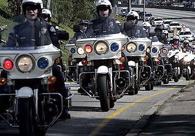 Hundreds of police officers escort hearse with body of slain LAPD officer Ricardo Lizarraga along the Santa Monica Freeway exiting at Crenshaw Blvd. Friday afternoon. Lizzarage was killed in the line of duty last week.