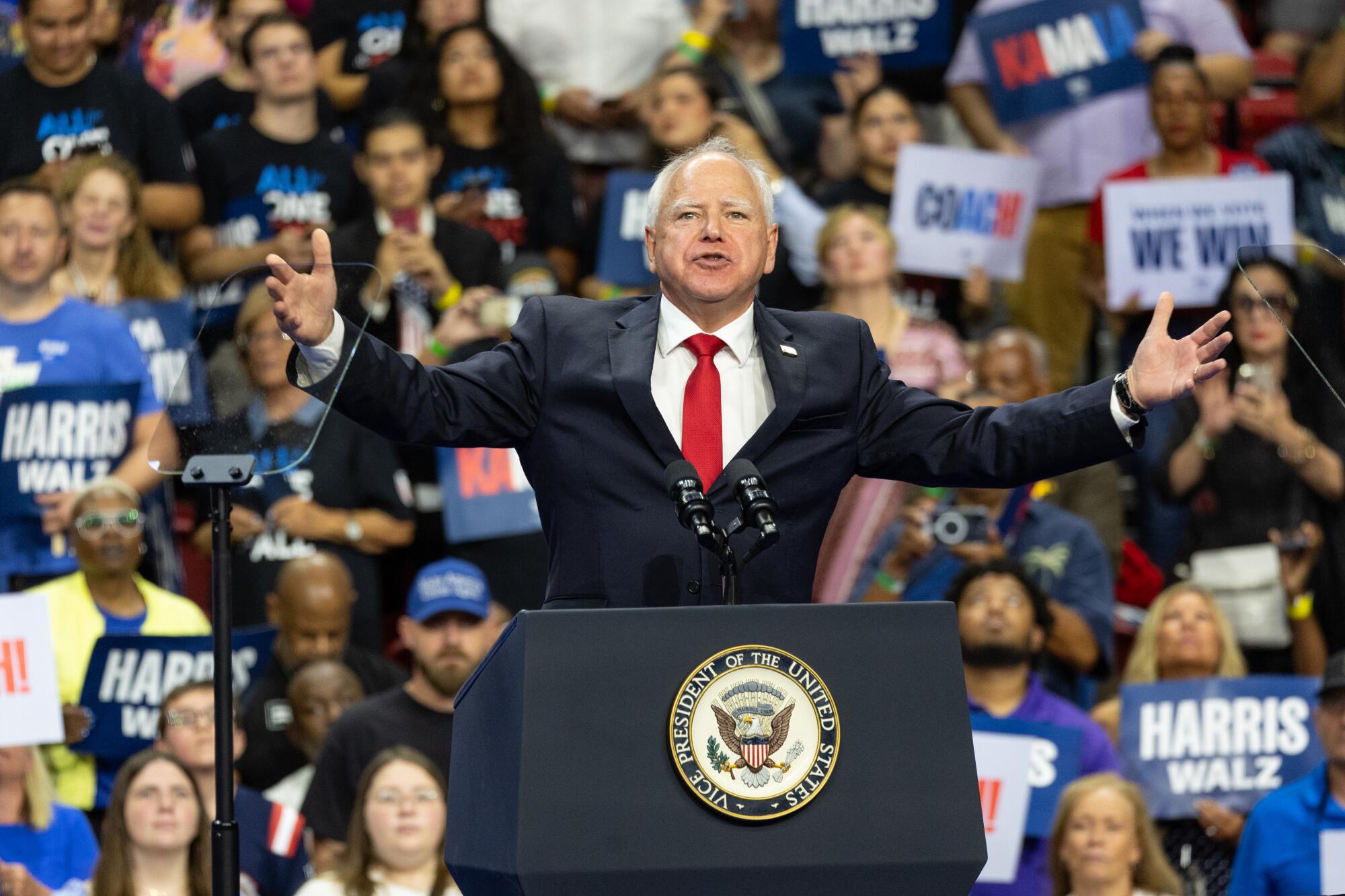 Minnesota Governor Tim Walz spreads his arms wide as he speaks at a lectern.